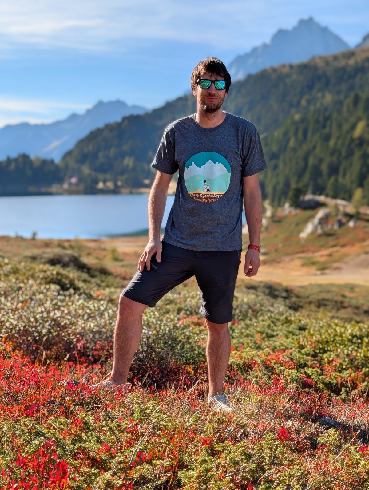 The Geislers men's t-shirt with front print, worn on an autumn hike by an alpine lake