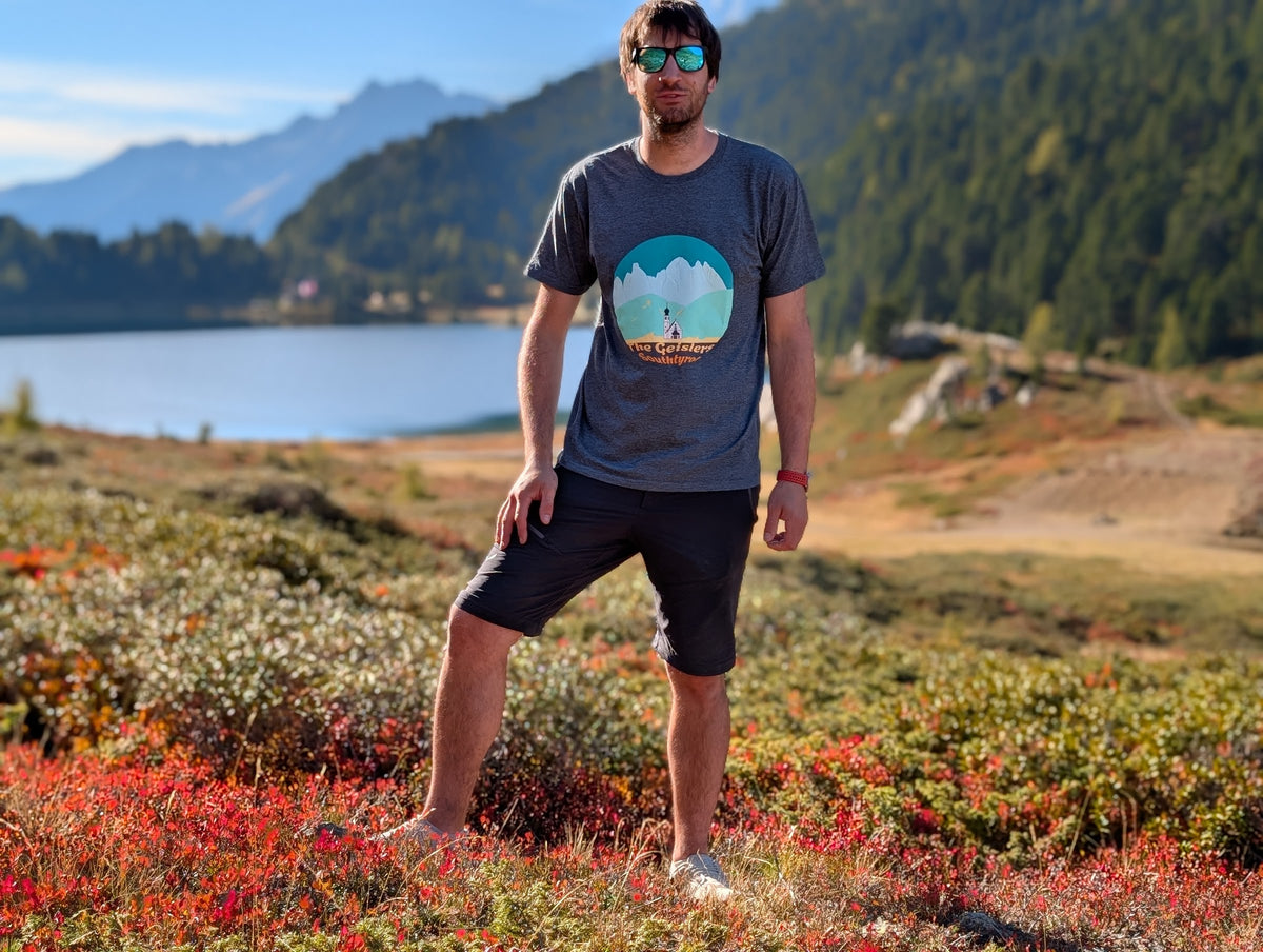 The Geislers men's t-shirt with front print, worn on an autumn hike by an alpine lake