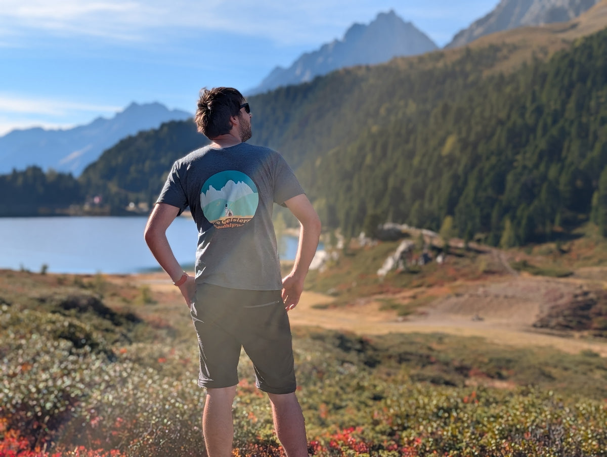 The Geislers men's t-shirt with large back print, worn on an autumn hike by an alpine lake