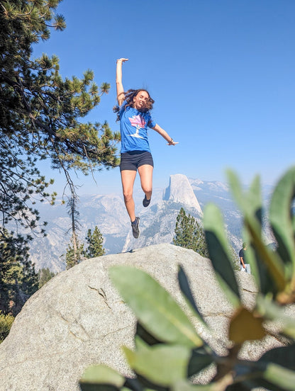 Happy hiker jumping in front of Half Dome at Glacier Point, Yosemite