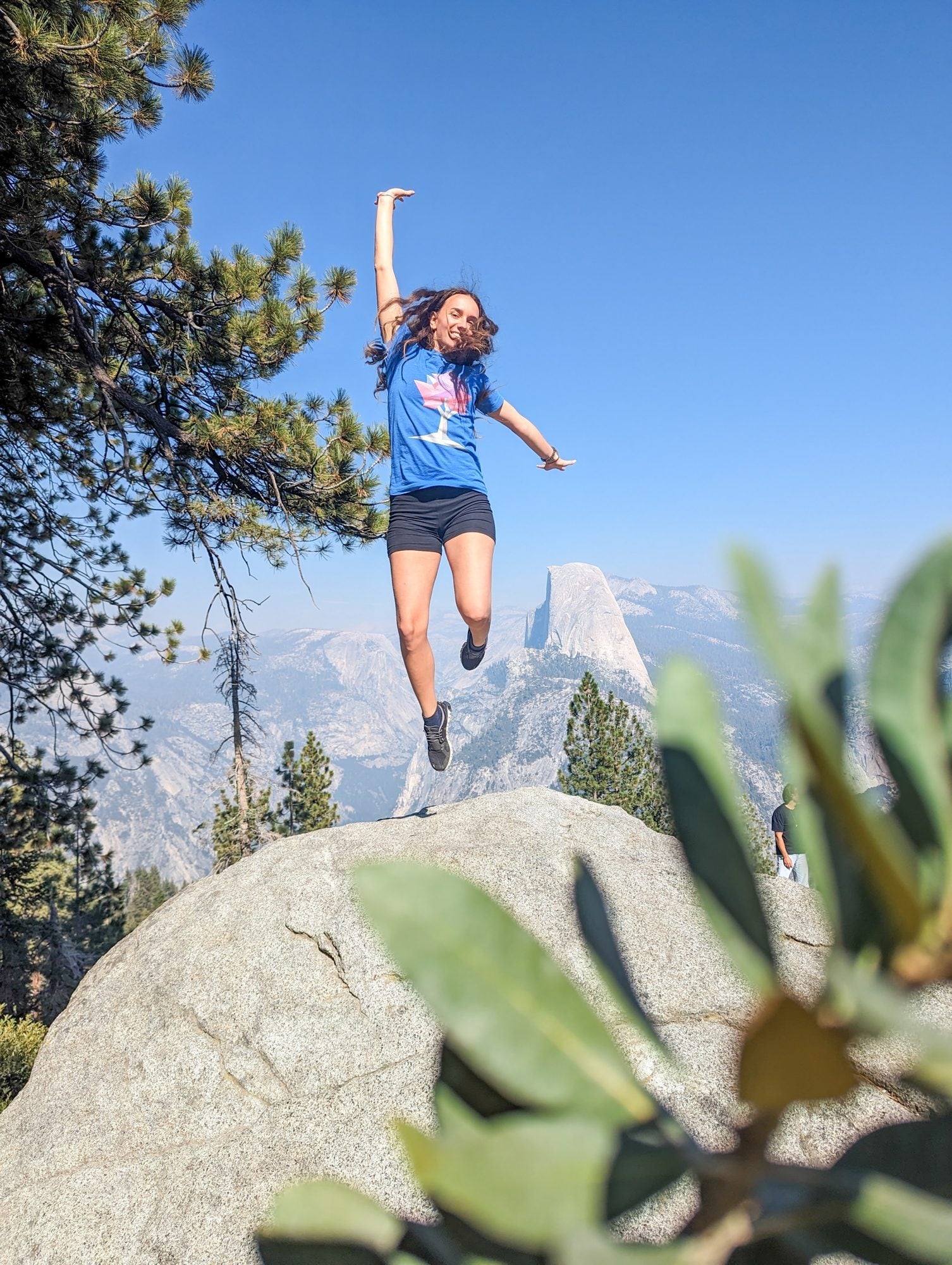 Happy hiker jumping in front of Half Dome at Glacier Point, Yosemite National Park