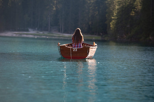Woman in a wooden rowing boat on the turquoise water of Lago di Braies, Dolomites