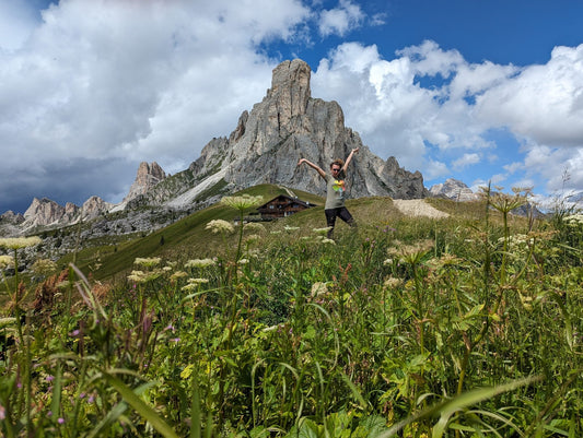 Hiker in a flower meadow below Ra Gusela at Passo Giau, Dolomites